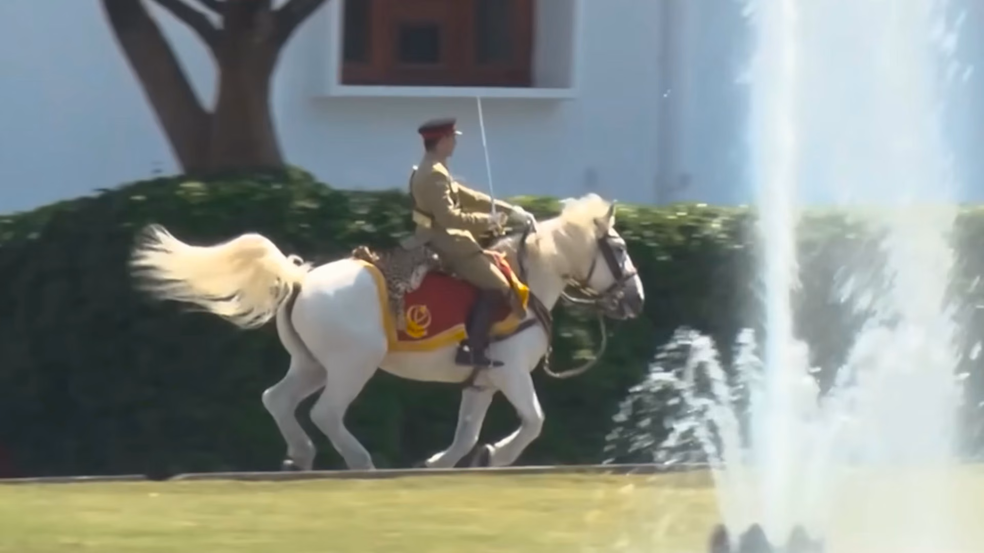 Mounted officer in ceremonial uniform riding past a fountain on the parade ground at Pakistan Military Academy, Kakul.